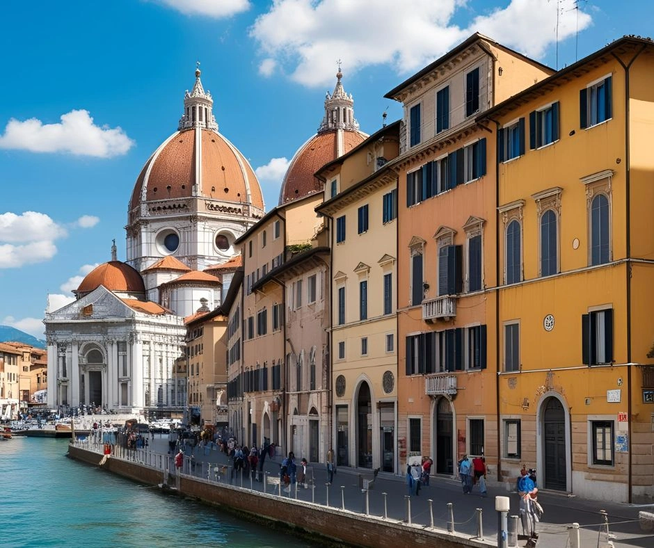 A scenic view of a canal-side street in Italy, featuring colorful buildings and a grand domed cathedral under a bright blue sky.